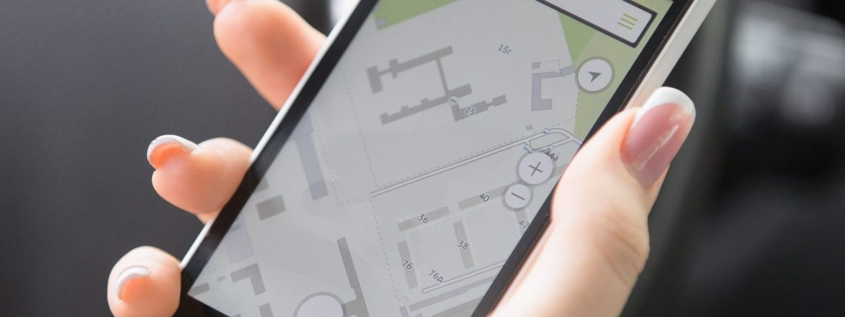 Close up of traveler female hand holding her smart phone. Young woman traveling by car using GPS instead of a paper map, to see destination, checking travel time and distance for available route